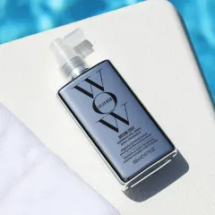 Color Wow Produkt auf einer hellen Oberfläche neben einem Handtuch und blauem Wasser im Hintergrund.